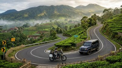 Motor touring dan mobil yang melintasi jalan berkelok menuju kawasan pegunungan.