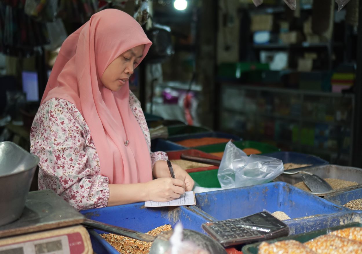 Pelaku UMKM menghitung biaya bahan baku dan mencatat keuangan usaha untuk menjaga arus kas serta keuntungan bisnis.