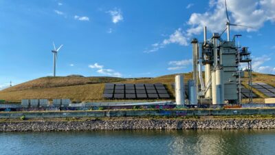 Panel surya dan turbin angin sebagai gambaran transisi energi global menuju sistem energi rendah emisi.